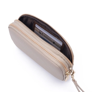 Macro detail of beige pebble leather wristlet with dual zippers and gold-tone hardware