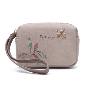 Detail of pink PU leather wallet with printed leaves and golden bird metallic ornament