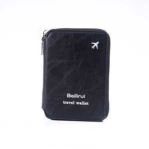 Détail du portefeuille de voyage en cuir noir avec breloque avion et fermeture éclair