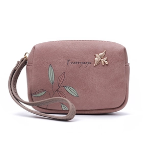 Detail of dusty rose PU leather wallet featuring leaf print and gold bird ornament