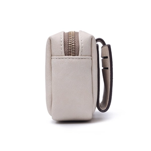 Detailed macro view of the cream PU leather texture and durable metal zipper of the wallet