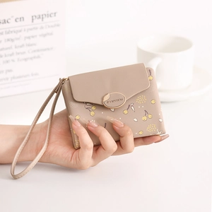 Close-up of khaki PU leather wallet with berry print, hand strap and metal leaf detail
