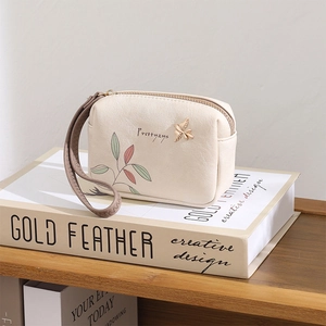 Detail of cream PU leather wallet with floral print and metallic bird accent strap