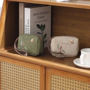 Close-up of olive and cream PU leather wallets with bird charm and floral prints