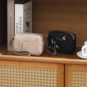Detail view of floral print PU leather wallets with bird zippers on a wooden shelf
