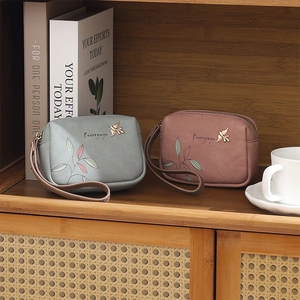 Detail of grey and pink PU leather wallets with leaf print and bird metal hardware