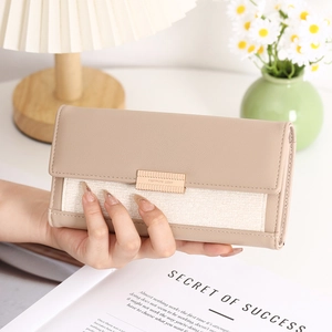 Detail of a khaki leather and off-white canvas long wallet with a gold nameplate