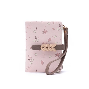 Détail du portefeuille rose à fleurs, imprimé cerise, lanière brune et boucle trèfle