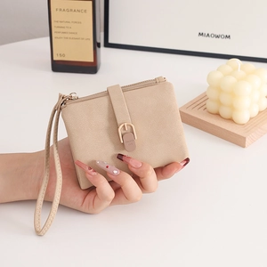 Détail du portefeuille beige clair en cuir PU mat avec boucle métal et dragonne