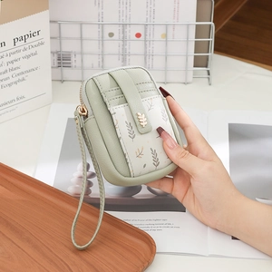 Détail du mini sac vert clair en simili cuir avec boucle feuille dorée et motifs feuilles