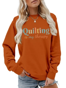Detail of orange crewneck sweatshirt featuring retro Quilting is my therapy text