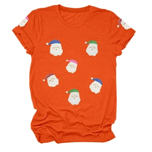 Détail d'un t-shirt de Noël orange avec des motifs de Père Noël en paillettes colorées