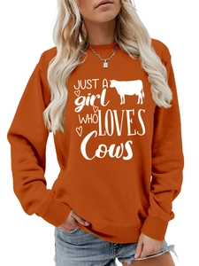 Detail of orange crewneck sweatshirt featuring white Just a Girl Who Loves Cows print