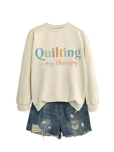 Detail of off-white sweatshirt with Quilting is my therapy text and ripped denim shorts