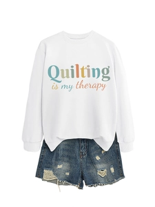 Detail of white crewneck sweatshirt with 'Quilting is my therapy' print and denim shorts
