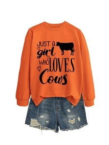 Close-up of bright orange sweatshirt with cow print paired with distressed denim shorts