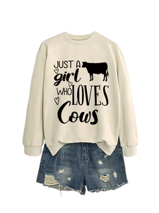 Detail of off-white crewneck sweatshirt with cow print and distressed blue denim shorts