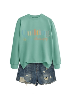 Detail of mint green sweatshirt with Quilting is my therapy text and distressed denim shorts