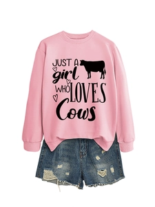 Flat lay detail of pink sweatshirt with cow slogan and distressed blue denim shorts