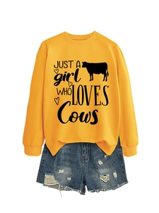 Close-up of ginger yellow sweatshirt with Just a girl who loves cows print and blue denim shorts