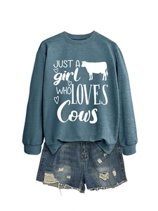 Detail of cow-themed graphic print on teal sweatshirt with distressed denim shorts