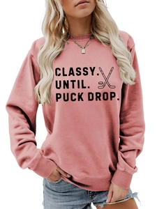 Close-up of mauve crewneck sweatshirt featuring classy until puck drop hockey slogan print