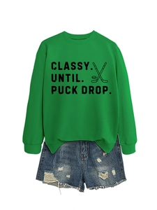 Detailed flat lay of bright green hockey sweatshirt with denim shorts on white background