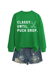 Close-up of bright green sweatshirt featuring ribbed cuffs and ice hockey print graphics