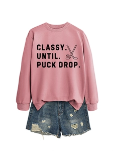 Detail of pink crewneck sweatshirt with hockey slogan and distressed denim shorts