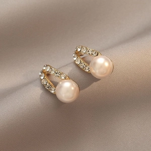 Elegant gold U-shaped pearl earrings with cubic zirconia on champagne silk backdrop