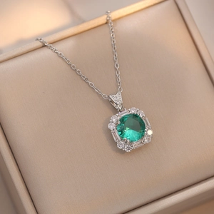 Macro shot of emerald green pendant necklace with zircon halo in premium jewelry box