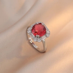 Macro shot of silver adjustable ring with large red zircon centerpiece on silk