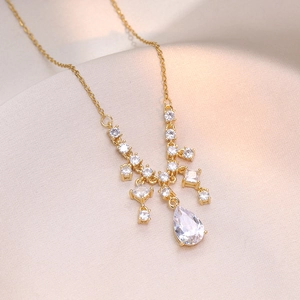 Collier doré élégant avec pendentif en zircon goutte sur fond de soie champagne