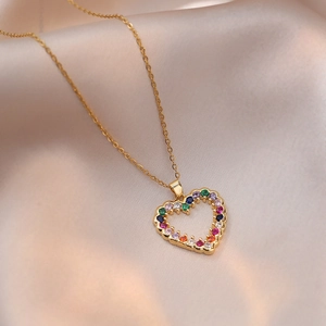 Collana con ciondolo a cuore dorato e zirconi colorati su sfondo di raso beige