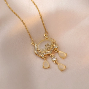 Golden Ruyi lock necklace with cat eye stone and teardrop charms on silk background