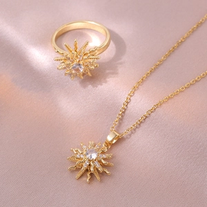 Golden flower necklace and ring set with sparkling cubic zirconia on purple silk