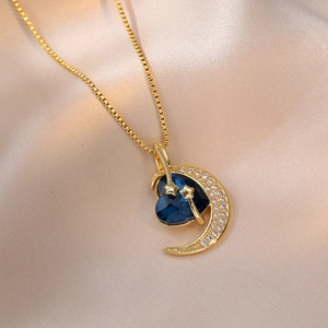 Collier en or avec pendentif cœur bleu et lune en zircons sur fond en soie chic