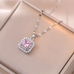 Macro detail of silver necklace with princess cut pink gem and double diamond halo