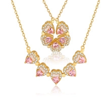 Detail of gold clover necklace unfolding into four pink heart pendants with zircon accents
