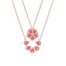 Macro shot of rose gold cherry blossom pendants with pink enamel and micro-pave diamonds