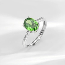 Macro view of adjustable silver ring featuring a large oval green gemstone and side diamonds