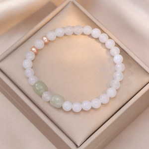 Détail d'un bracelet en quartz fraise avec perles baroques dans un coffret cadeau doré