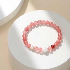 Bracelet en quartz fraise rose avec perle baroque sur un présentoir blanc pur