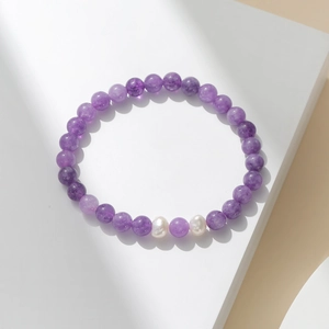 Détail des perles en cristal violet et perles baroques sur un bracelet élastique