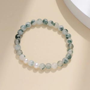 Détail de perles d'agate mousse aux textures naturelles et perles blanches sur fond épuré