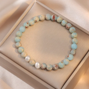 Gros plan de perles baroques et pierres naturelles bleues sur un coffret à bijoux doré