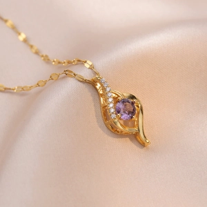 Gold leaf pendant necklace with purple gemstone and pavé zircons on silk background