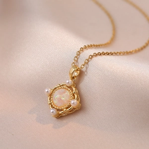 Chic gold necklace with gradient opal stone and pearl accents on silk background