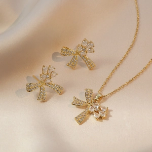 Parure de bijoux élégante avec nœud doré et zircons scintillants, collier et boucles
