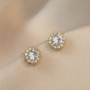Elegant gold zircon flower stud earrings displayed on premium champagne silk fabric
